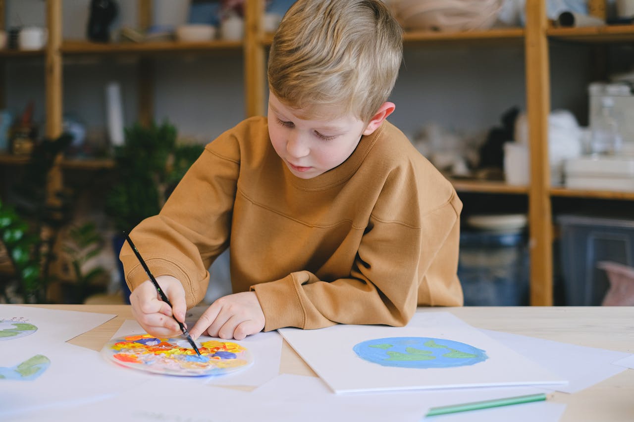 Young boy painting at a table, practicing arts and crafts indoors.