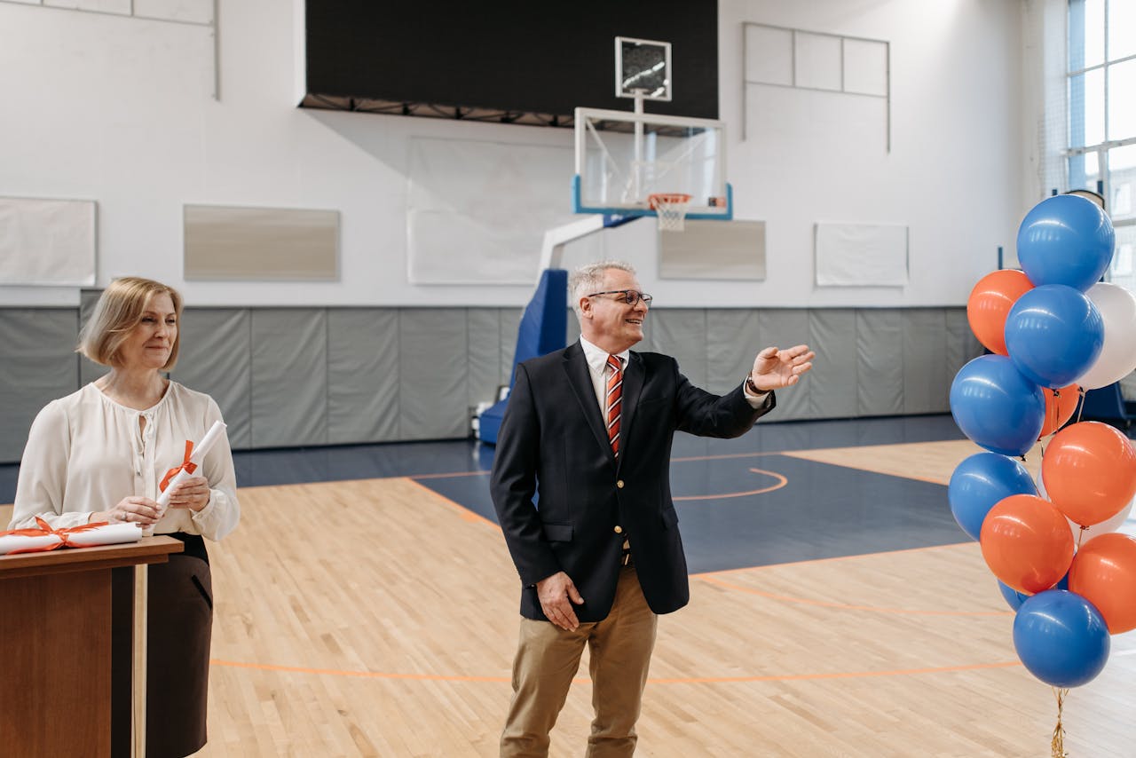 School ceremony in a gymnasium with a teacher and official celebrating.